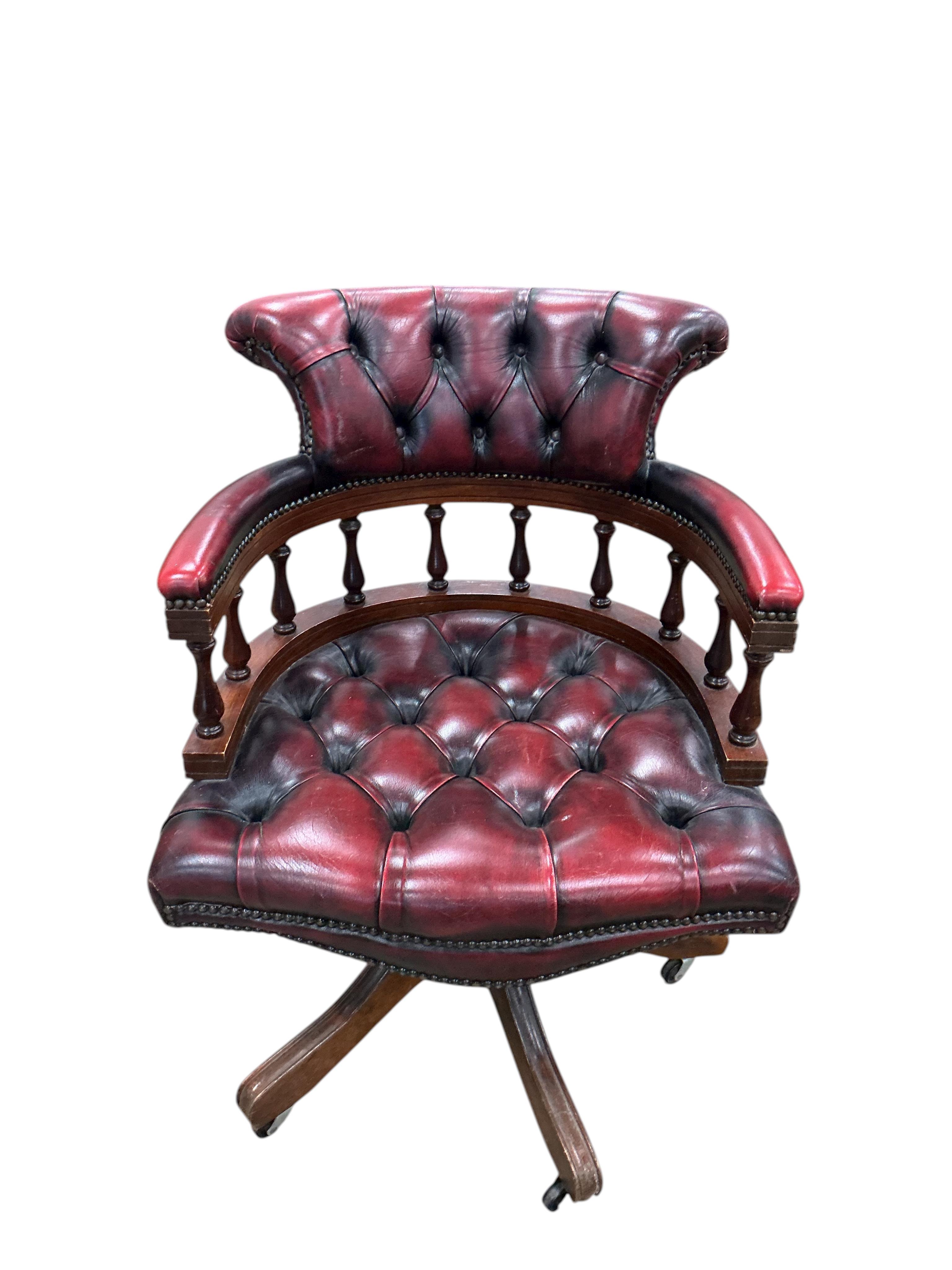 A late 20th century revolving desk chair upholstered in buttoned claret leather, width 62cm, depth 56cm, height 82cm